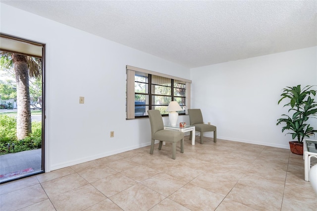 living area featuring a textured ceiling and light tile patterned floors