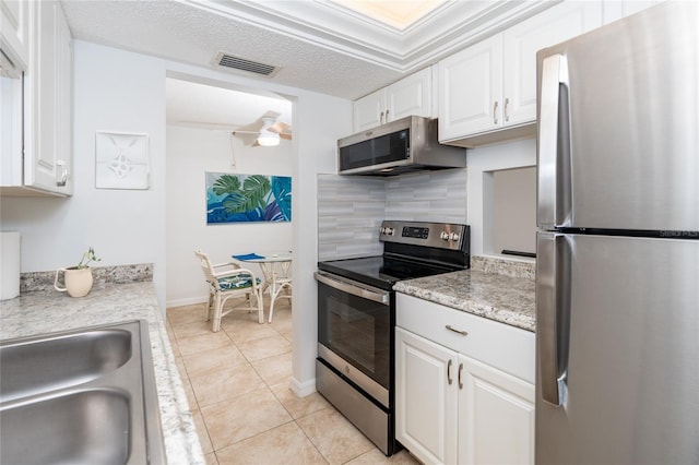 kitchen featuring ceiling fan, white cabinets, decorative backsplash, appliances with stainless steel finishes, and light tile patterned floors