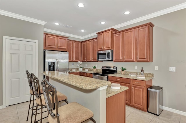 kitchen with crown molding, a breakfast bar, light tile patterned floors, a kitchen island, and appliances with stainless steel finishes