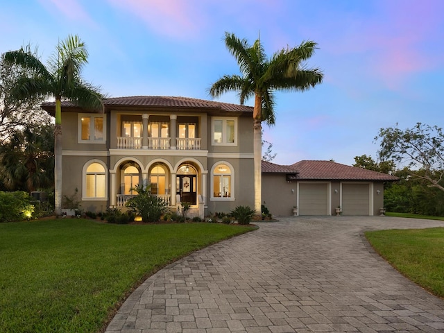 mediterranean / spanish house featuring a garage and a yard