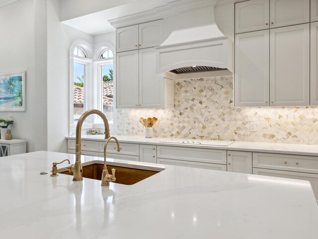 kitchen featuring custom range hood, light stone counters, electric cooktop, and tasteful backsplash