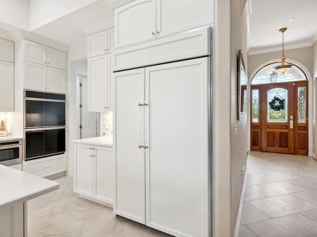 kitchen with double oven, white cabinetry, decorative light fixtures, crown molding, and light tile patterned flooring