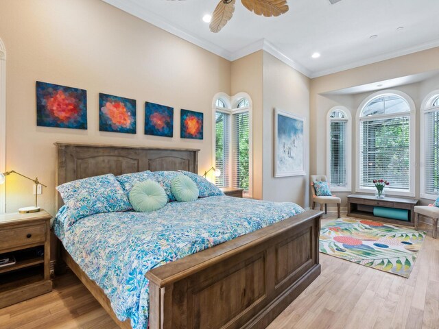 bedroom featuring light hardwood / wood-style flooring, ceiling fan, multiple windows, and ornamental molding