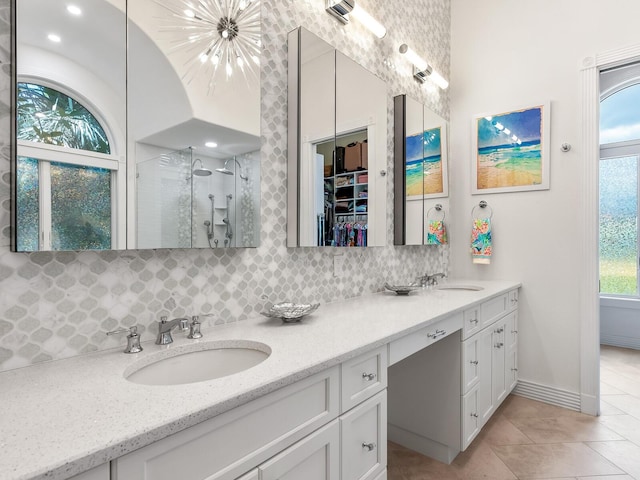 bathroom with double vanity, a shower stall, decorative backsplash, and a sink