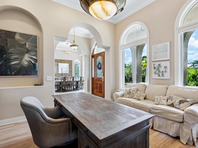 interior space featuring ornamental molding, light wood-style flooring, and baseboards