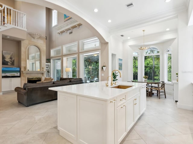 kitchen with light tile patterned floors, a fireplace, a sink, visible vents, and crown molding