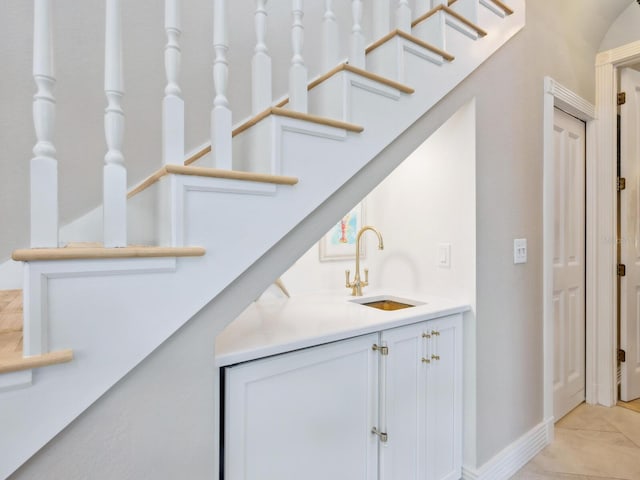 bar featuring baseboards, a sink, and light tile patterned flooring