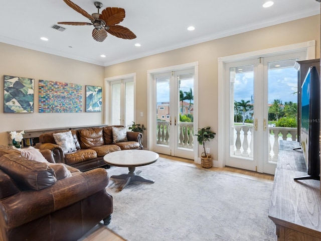 living room featuring ceiling fan, french doors, crown molding, and light hardwood / wood-style flooring