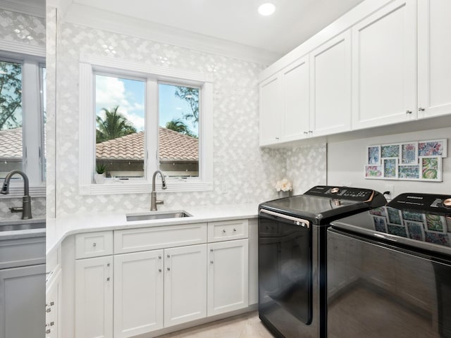 laundry room with sink, washing machine and clothes dryer, crown molding, and cabinets