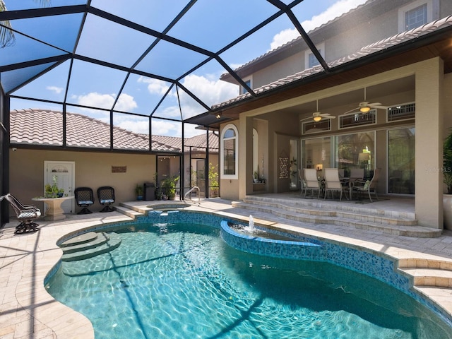 view of pool featuring glass enclosure, a pool with connected hot tub, a ceiling fan, and a patio