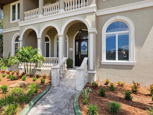 view of exterior entry featuring a porch and stucco siding