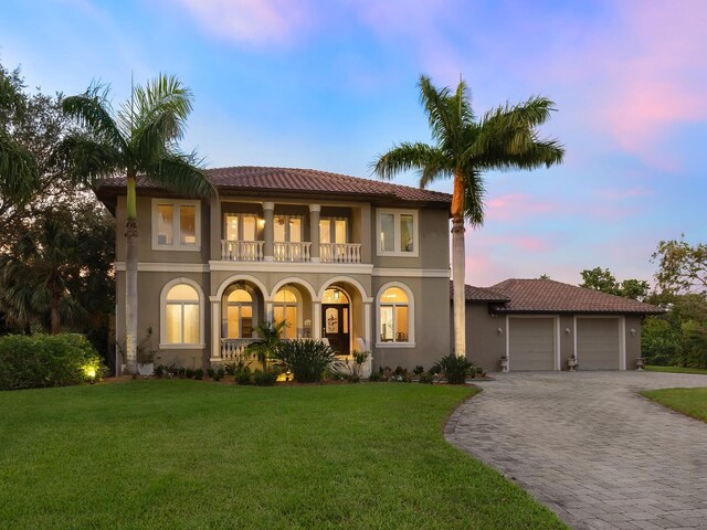 mediterranean / spanish home featuring a garage, a balcony, and a lawn