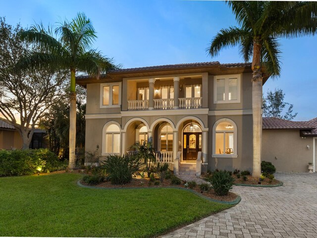 mediterranean / spanish house featuring a balcony and a lawn