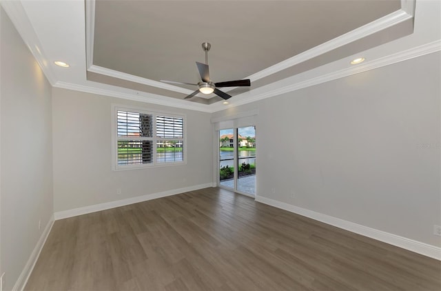 spare room featuring a raised ceiling, ornamental molding, hardwood / wood-style floors, and ceiling fan