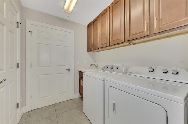 washroom with washing machine and clothes dryer, sink, light tile patterned floors, and cabinets