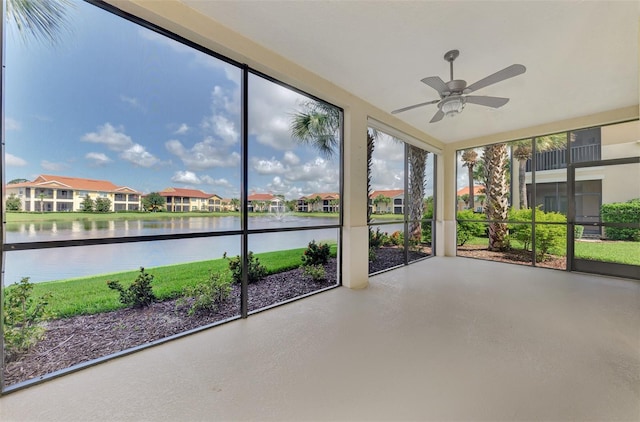 unfurnished sunroom featuring a wealth of natural light, ceiling fan, and a water view