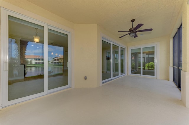 unfurnished sunroom with a wealth of natural light, a water view, and ceiling fan