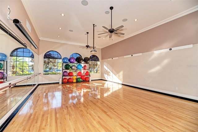 game room featuring ornamental molding, a towering ceiling, and light hardwood / wood-style flooring