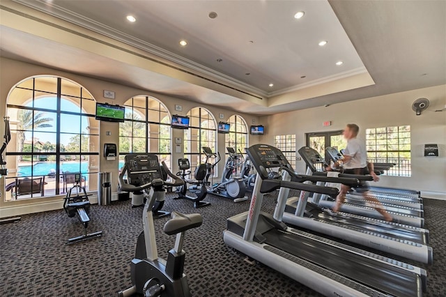 gym with a raised ceiling and ornamental molding