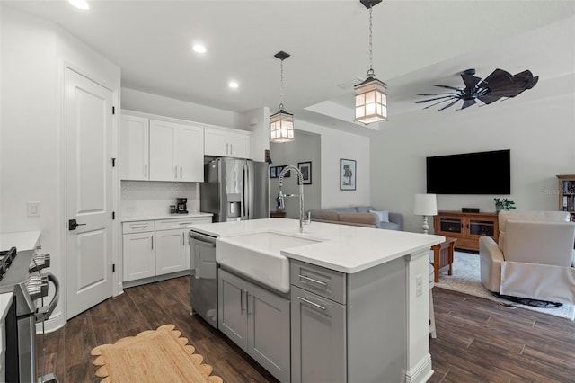 kitchen featuring appliances with stainless steel finishes, a kitchen island with sink, hanging light fixtures, ceiling fan, and dark hardwood / wood-style floors