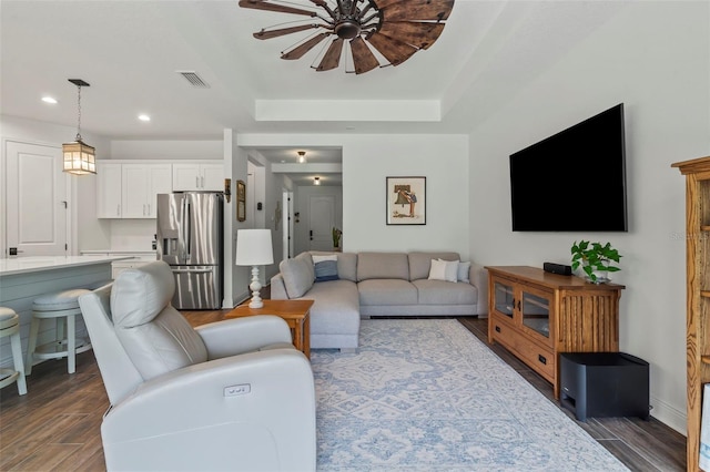 living room with a raised ceiling and dark hardwood / wood-style floors