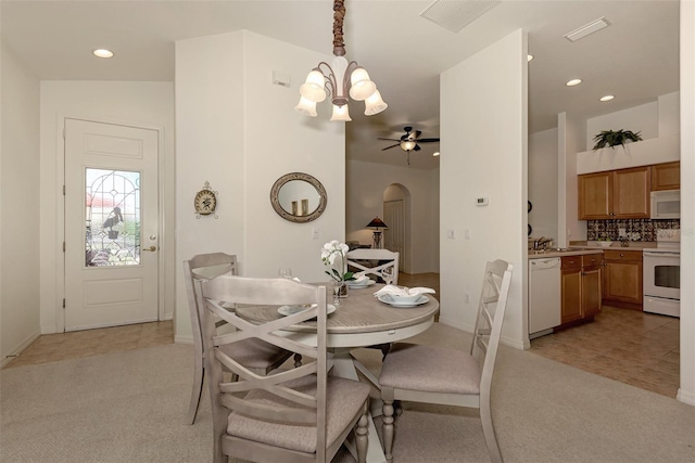 dining space featuring ceiling fan with notable chandelier, vaulted ceiling, sink, and light carpet