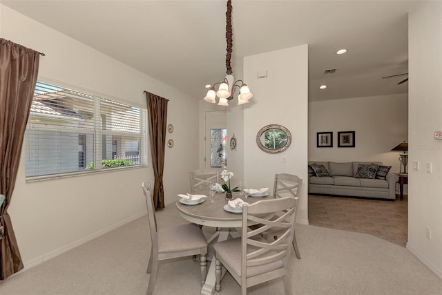 dining room with light colored carpet and ceiling fan with notable chandelier