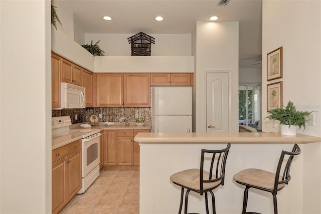 kitchen featuring light tile patterned flooring, a kitchen breakfast bar, white appliances, tasteful backsplash, and light brown cabinets