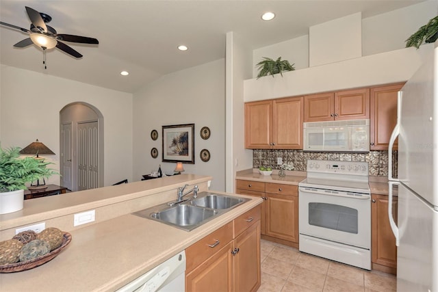 kitchen featuring backsplash, sink, light tile patterned floors, white appliances, and ceiling fan