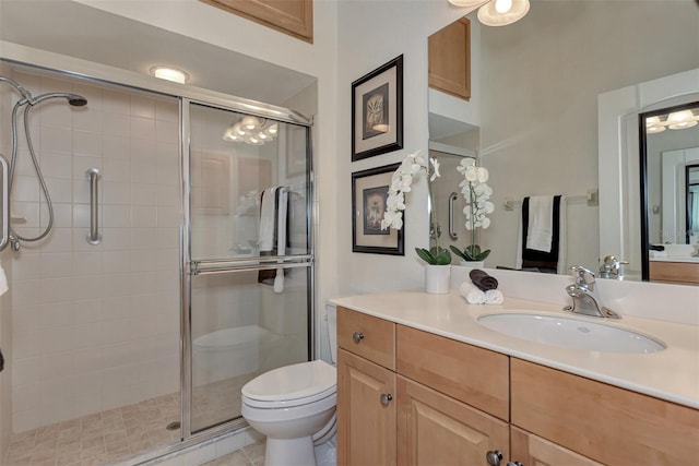 bathroom featuring tile patterned floors, toilet, vanity, and a shower with shower door