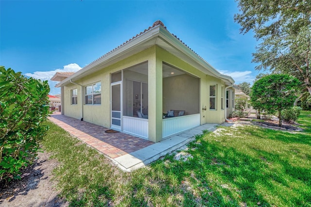 rear view of property featuring a sunroom and a yard