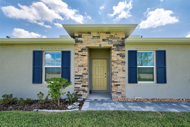 doorway to property featuring stone siding and stucco siding