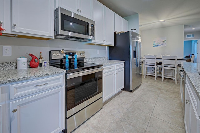 kitchen featuring stainless steel appliances, light stone countertops, visible vents, and white cabinetry