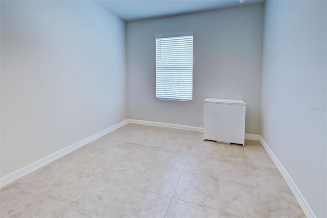 empty room with light tile patterned floors and baseboards