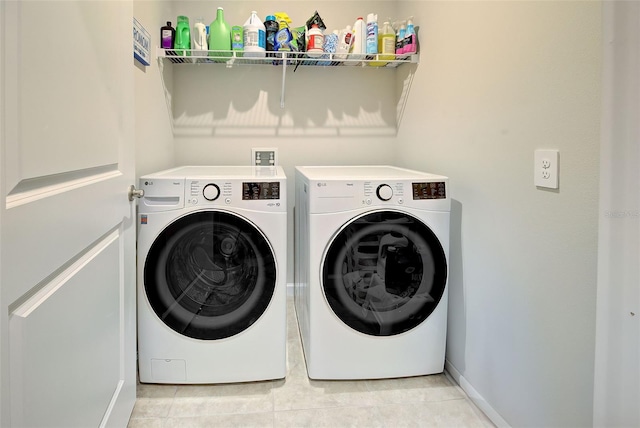 laundry room featuring washing machine and dryer, laundry area, baseboards, and light tile patterned floors