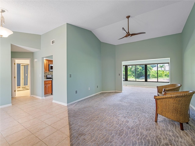 living area with ceiling fan, a textured ceiling, light colored carpet, and high vaulted ceiling