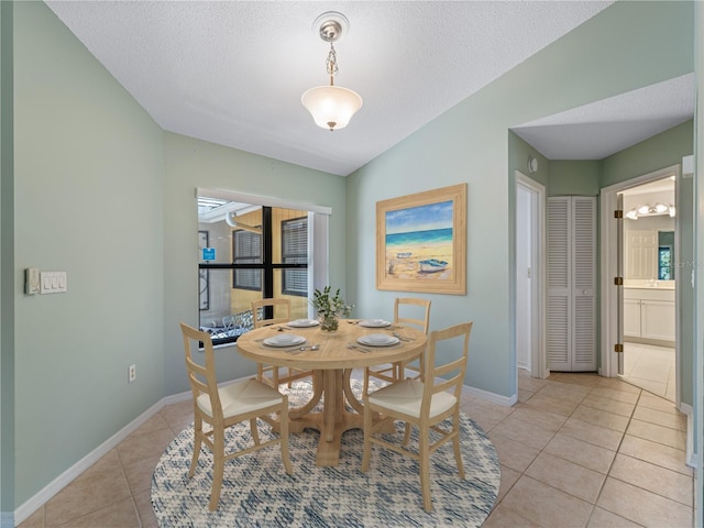 dining area featuring lofted ceiling, a textured ceiling, and light tile patterned floors