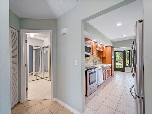 kitchen with decorative backsplash, appliances with stainless steel finishes, french doors, and light tile patterned floors