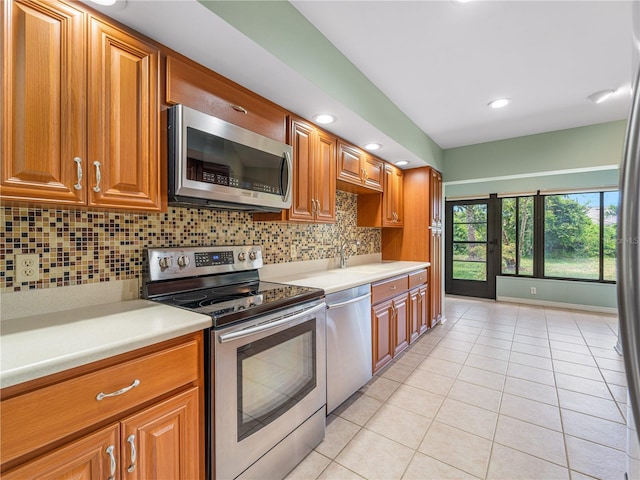 kitchen featuring tasteful backsplash, sink, stainless steel appliances, and light tile patterned floors