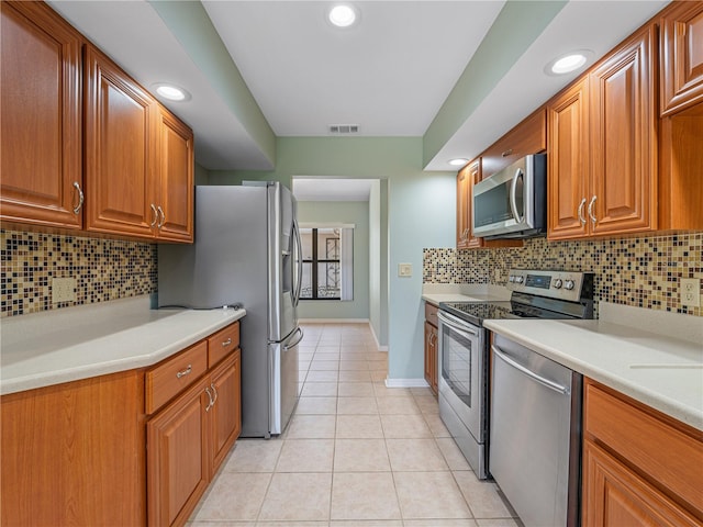 kitchen featuring decorative backsplash, appliances with stainless steel finishes, and light tile patterned floors