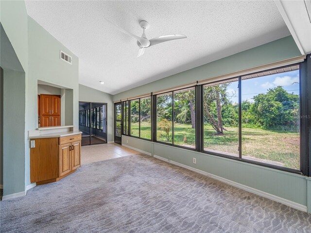 kitchen featuring ceiling fan, a textured ceiling, light carpet, and vaulted ceiling