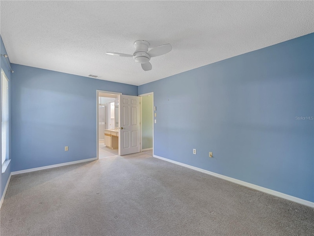 empty room featuring a textured ceiling, light colored carpet, and ceiling fan