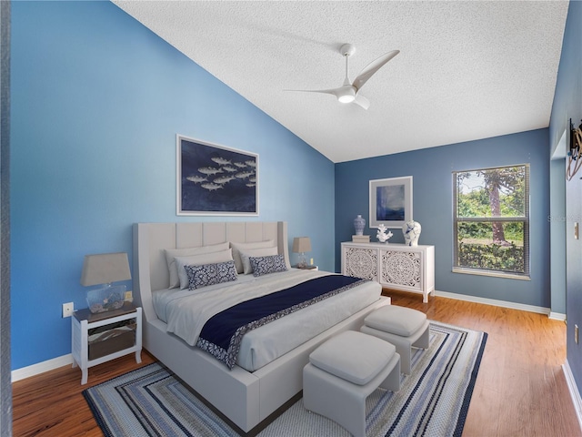 bedroom with ceiling fan, vaulted ceiling, a textured ceiling, and hardwood / wood-style floors