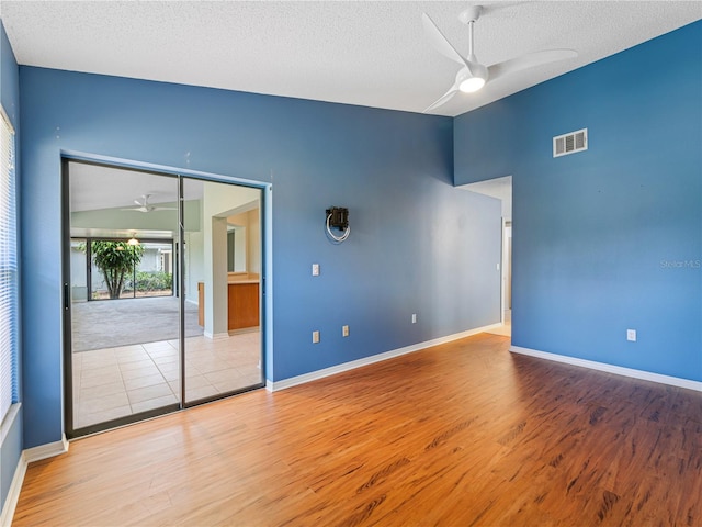 spare room featuring ceiling fan, light hardwood / wood-style flooring, a textured ceiling, and lofted ceiling