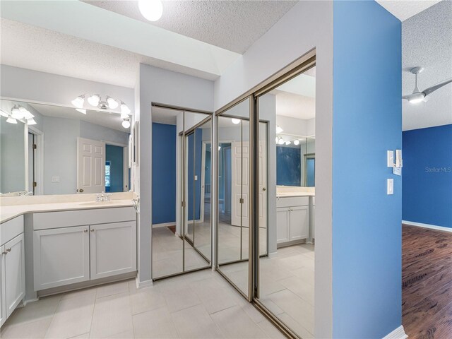 bathroom with ceiling fan, vanity, a textured ceiling, and hardwood / wood-style flooring