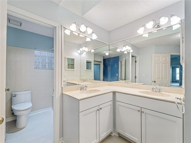 bathroom featuring double sink vanity, a textured ceiling, tile patterned flooring, and toilet