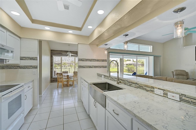 kitchen with ceiling fan, plenty of natural light, a tray ceiling, and decorative light fixtures