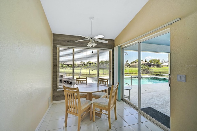 tiled dining space featuring ceiling fan and vaulted ceiling