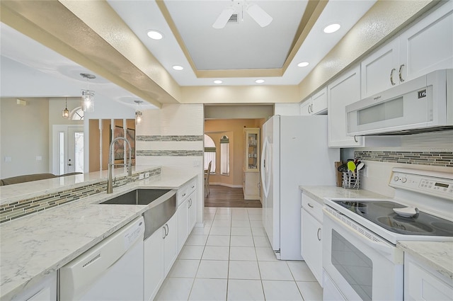 kitchen with ceiling fan, a raised ceiling, light hardwood / wood-style flooring, white cabinets, and white appliances