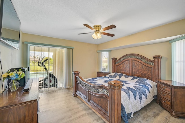 bedroom with a textured ceiling, ceiling fan, multiple windows, and light wood-type flooring